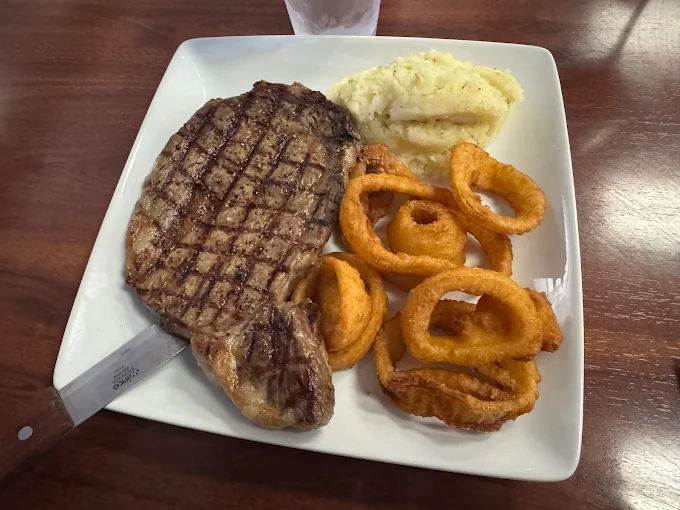 Ribeye steak with onion rings and mashed potatoes